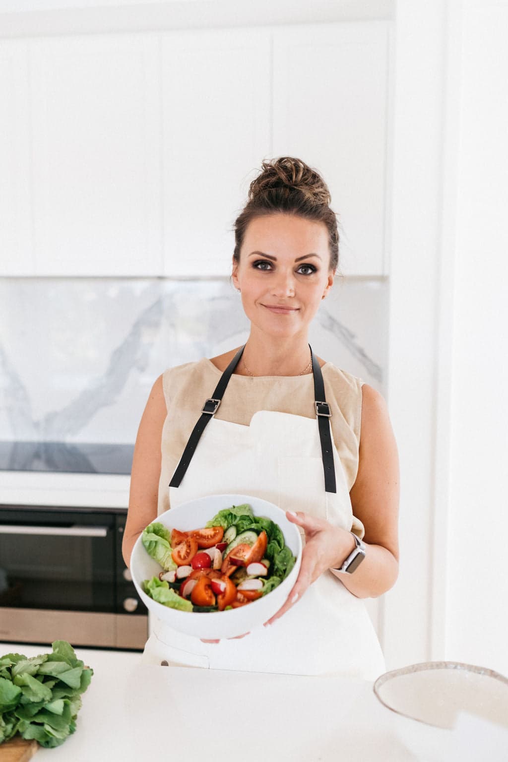 Zhanna Gee, founder of Slim By Nature, in her kitchen holding a fresh salad